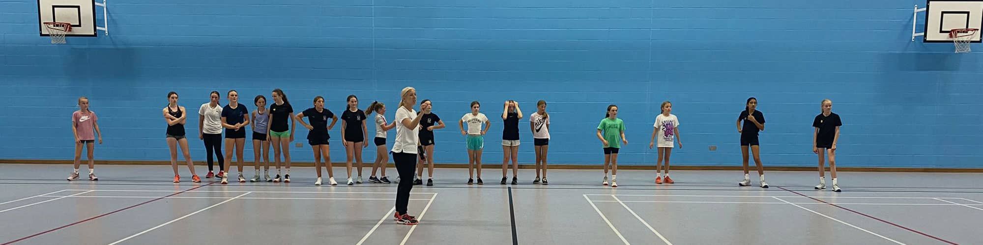 Teenage girls at indoor netball lesson in Cheshire school